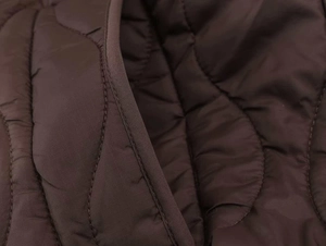 Détail du tissu matelassé marron avec coutures de précision et léger éclat satiné