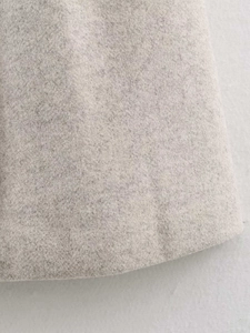 Close-up of light grey wool blend coat hem showing detailed fabric texture and stitching