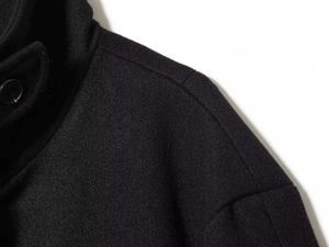 Detail of black wool coat showing standing collar design and premium fabric texture