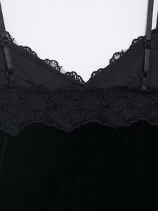 Détail du caraco en velours noir montrant la dentelle fine et la bretelle réglable