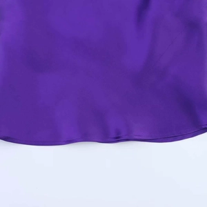 Close-up of the smooth hem stitching on a purple satin halter top with silk texture
