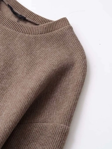 Detail shot of brown knit sweater featuring ribbed texture and high-quality crew neckline