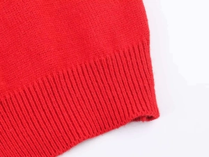 Detail shot of the red knitted cardigan showing premium ribbed cuffs and fine weave texture