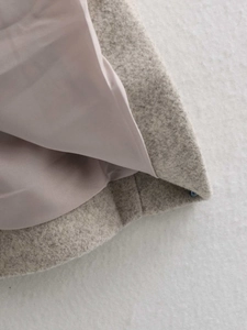 Detailed close-up of wool blend coat hem featuring oatmeal fabric and silk-like pink lining