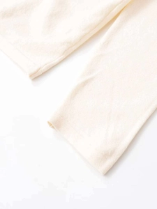 Close-up of off-white knitted fabric with textured pleats and detailed stitching
