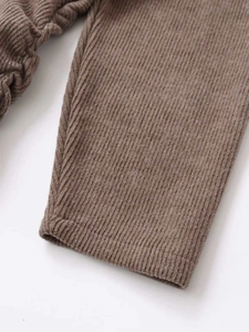 Detailed close-up of brown ribbed knit fabric texture on women's stylish autumn dress
