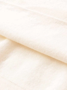 Macro shot of off-white knit texture showing soft wool-like pleated fabric details