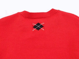Close-up of red knit sweater featuring black diamond embroidery on back collar