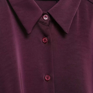 Close-up of a burgundy satin short shirt featuring a lapel collar and matching buttons