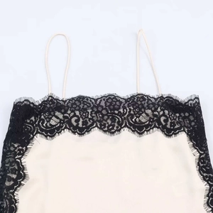 Detailed view of apricot silk satin camisole featuring delicate black eyelash lace trim
