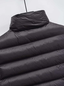 Detail of black reversible quilted vest featuring a stand collar and high-quality nylon fabric