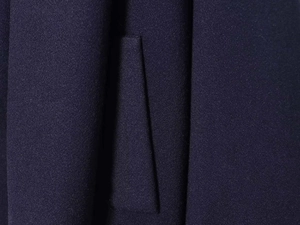 Macro view of navy blue wool blend fabric showing dense woven texture and seam details