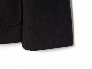 Close-up of the thick black wool blend fabric texture and hem on a commuter style jacket