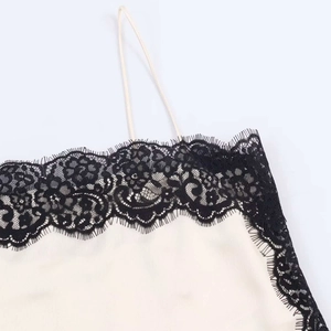 Detailed view of cream satin top featuring delicate black eyelash lace trim and thin straps