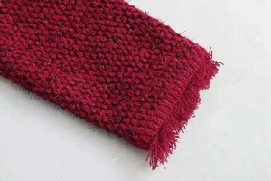 Gros plan sur le tissu en tweed bordeaux avec fils argentés scintillants et franges
