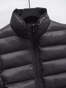 Detail of black quilted puffer vest showing stand collar and smooth metal zipper texture