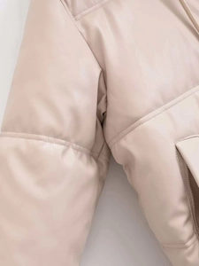 Detail of beige faux leather puffer jacket featuring quilted seams and zippered pockets