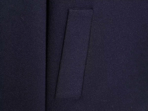 Macro view of seamless pocket stitching on a heavy navy wool blend cloak coat