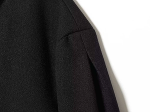 Macro shot showing the durable black wool blend fabric texture and stitching of the jacket