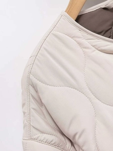 Macro view of wave quilted beige jacket featuring fine stitching and brown lining detail