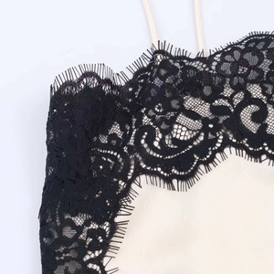 Detailed close-up of delicate black eyelash lace trim on a satin camisole top