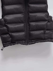 Close-up of quilted black puffer vest featuring a metal zipper and adjustable drawstring