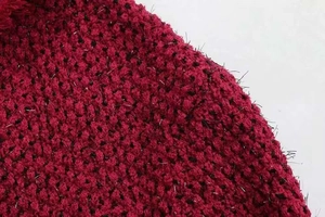 Gros plan sur un tricot en tweed bordeaux avec des fibres argentées et texture brillante