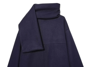 Detailed macro view of the premium thick wool texture and high collar on dark poncho coat