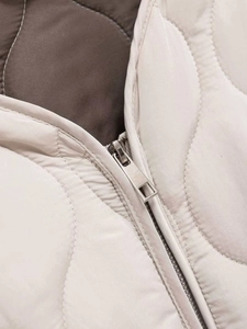 Detailed close-up of wavy quilted stitching and silver metal zipper on winter jacket