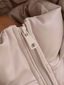 Detailed close-up of a matte beige faux leather jacket zipper and soft texture detail