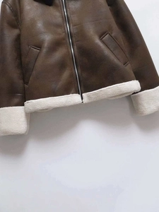 Detail of brown faux suede jacket with white shearling trim and silver metal zipper
