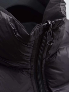Detail of windproof stand collar and smooth zipper on black padded vest for winter