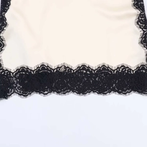 Detailed view of beige satin fabric combined with delicate black eyelash floral lace trim