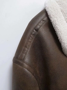 Detailed view of dark brown suede jacket with white faux shearling collar and stitching