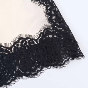 Close-up of beige satin fabric with delicate black eyelash lace trim and refined texture