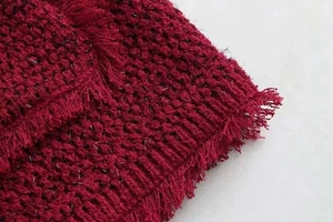 Gros plan sur le tissu en tweed rouge avec fils métalliques argentés et franges décoratives