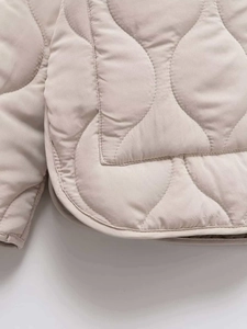 Close-up of onion-quilted beige jacket showing detailed stitching and fabric texture