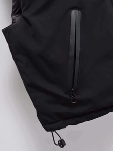 Close-up of waterproof zipper pocket and adjustable drawstring hem on black vest