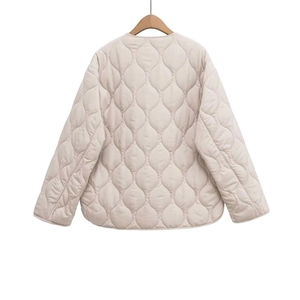 Detail of beige quilted jacket featuring onion stitch pattern on a wooden hanger