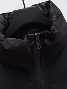 Close-up of windproof stand collar and metallic zipper on black padded vest jacket