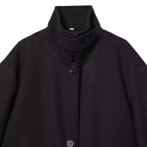 Minimalist black wool coat with stand collar and throat latch closure on white background