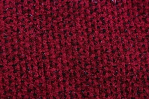 Gros plan sur un tissu en tweed rouge foncé avec fibres noires et fils d'argent brillants