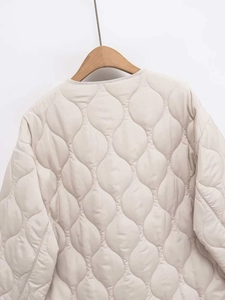 Detail of light beige quilted jacket showing precise gourd stitching and satin texture