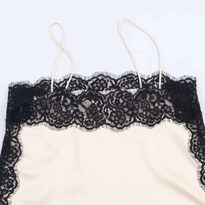 Detail of off-white satin camisole with delicate black lace trim and thin straps