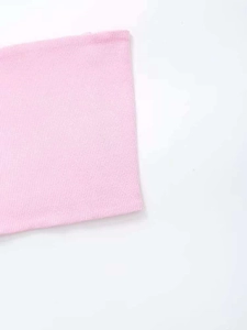 Detailed close-up of soft pink ribbed fabric texture and fine stitching on the garment