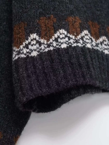 Detail of rib-knit cuffs with geometric jacquard pattern on charcoal gray sweater