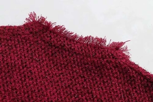 Détail du tissu en tweed bordeaux avec fils métalliques et bordures à franges