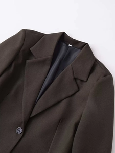 Macro detail of dark brown tailored blazer showing lapel collar and size S tag