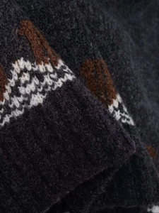 Detail of charcoal grey thick knit sweater featuring brown and white geometric jacquard patterns