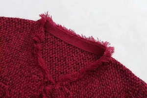 Détail du col en V avec bords effilochés sur veste en tweed bordeaux à fils dorés